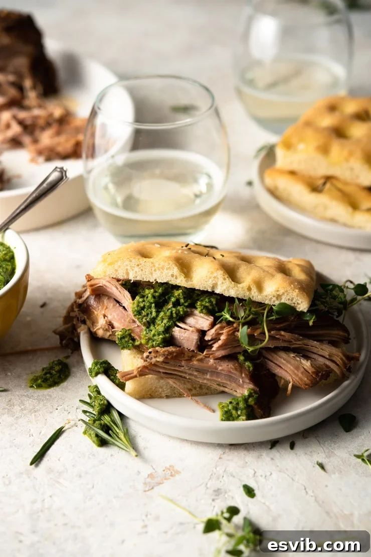 Delicious slow cooker pulled pork shoulder served on a sandwich with fresh herbs.