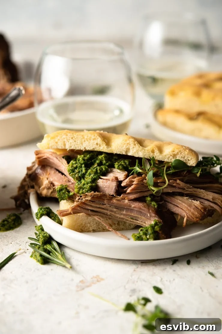 Close-up of shredded Italian pulled pork with salsa verde on a focaccia sandwich.