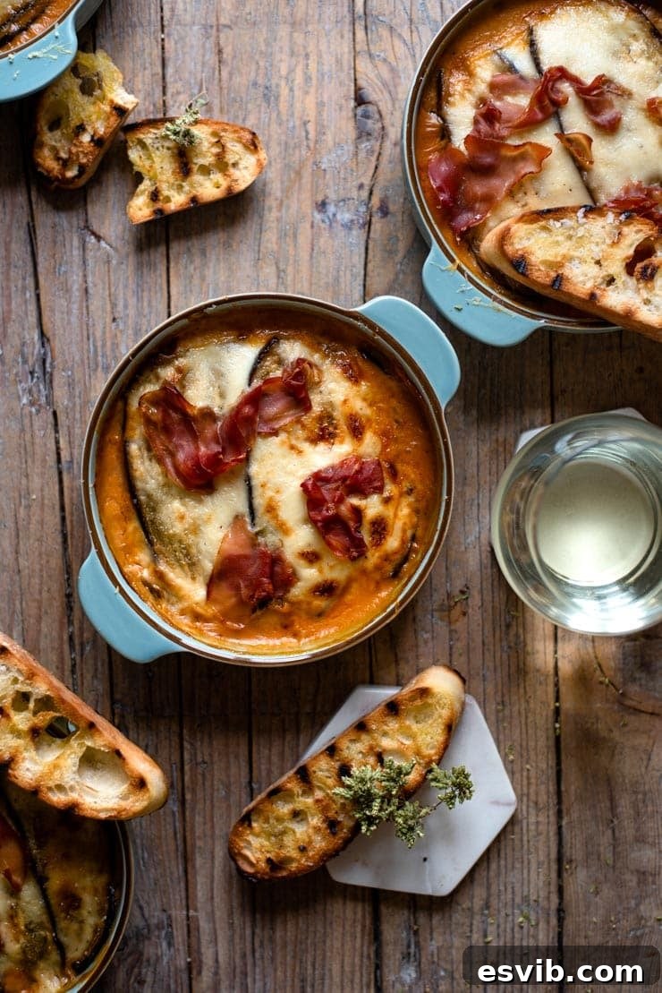 Delicious Low-Carb Eggplant Lasagna with Prosciutto and Mozzarella An overhead shot of eggplant lasagna with grilled ciabatta bread, showcasing its golden-brown top and rich layers.