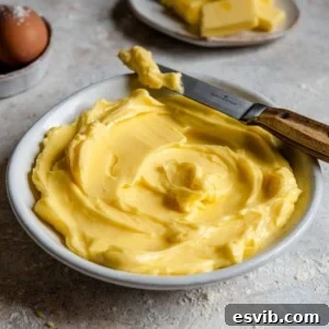 A close up side shot of perfectly softened butter in a bowl with a knife at the side.