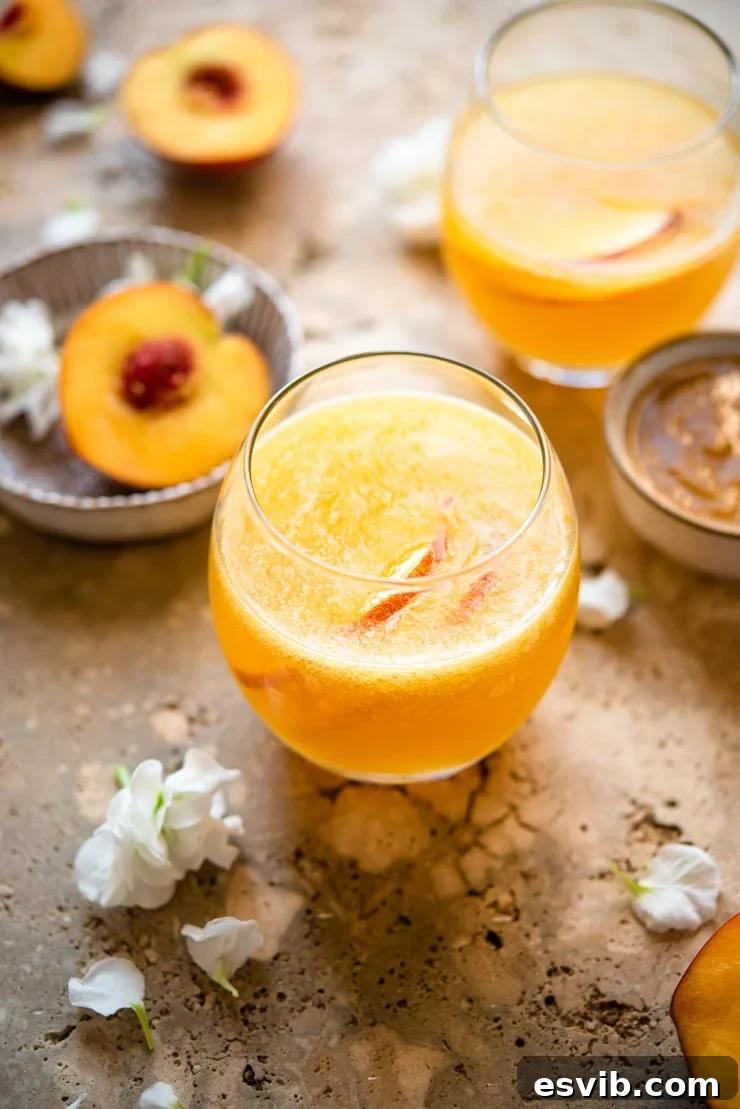 A classic Peach Bellini cocktail in an elegant glass, with fresh peaches and a bowl of peach puree artfully arranged in the background, signaling freshness and taste.