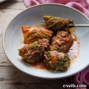 A plate of Italian Stuffed Cabbage Rolls with tomato sauce, garnished with fresh parmesan.