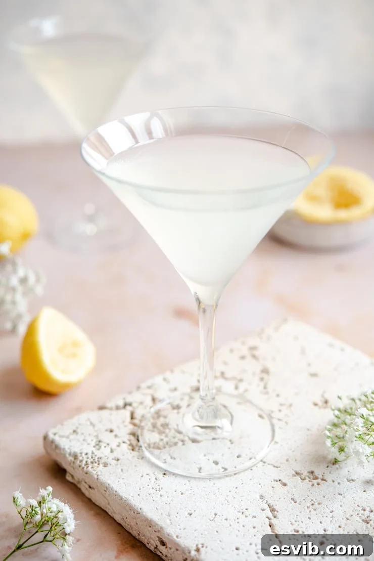 Side view of a vibrant Limoncello martini cocktail in a clear martini glass, showcasing its refreshing yellow hue.
