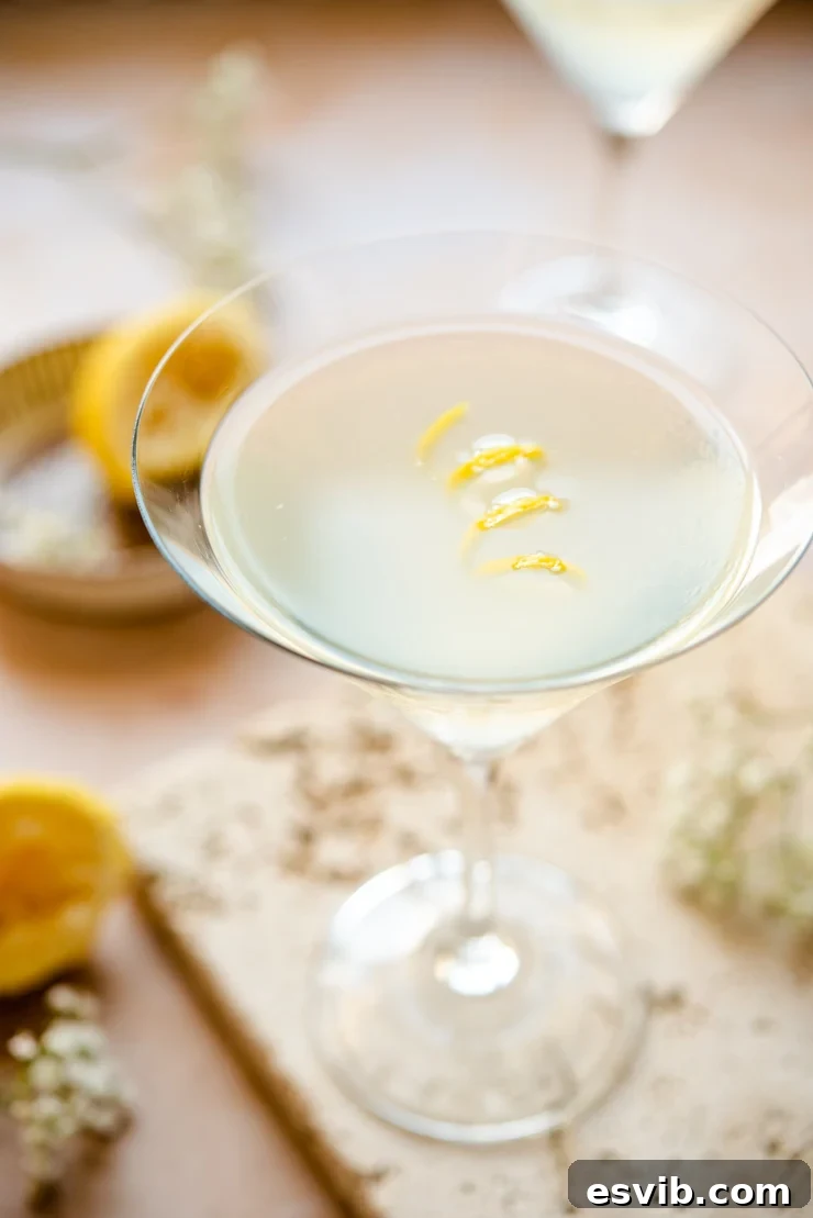 A close-up shot of a pristine Limoncello martini cocktail, exquisitely garnished with a coiled lemon peel in a classic martini glass.