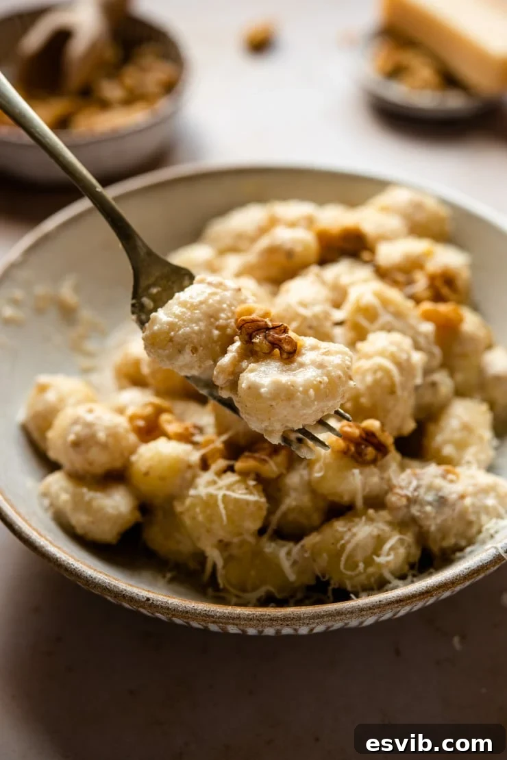 A close-up shot of creamy walnut sauce clinging to gnocchi on a fork, highlighting its luscious texture.
