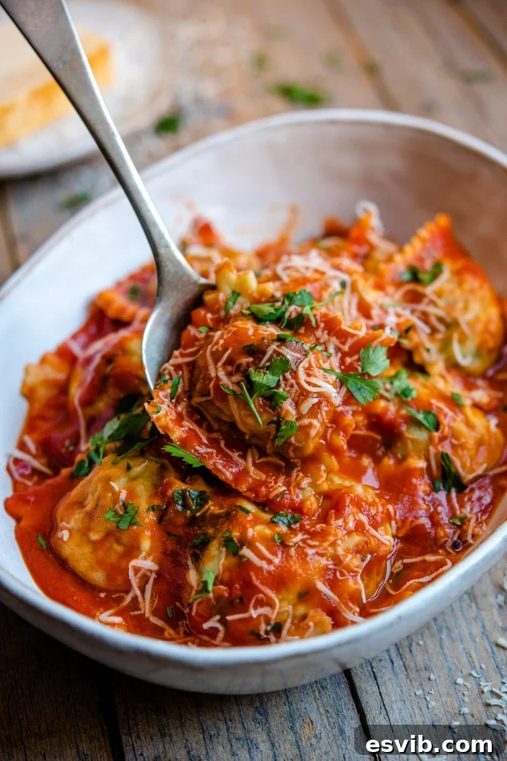 Homemade ravioli tossed with a vibrant tomato sauce in a bowl, garnished with fresh herbs