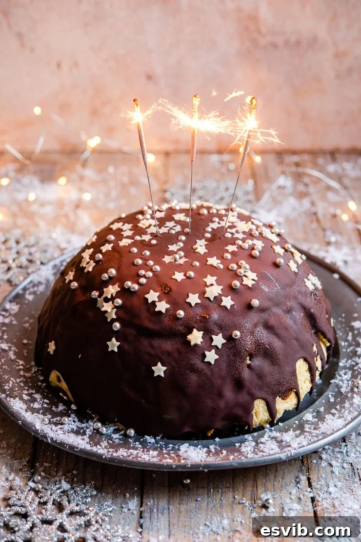 A side shot of a panettone bombe Christmas ice cream cake with sparklers, ready to be served as a festive Italian dessert.