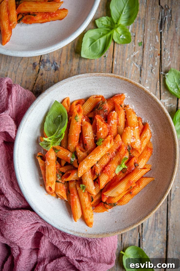 An overhead shot of vibrant Penne Pomodoro in a rustic bowl with fresh basil garnish