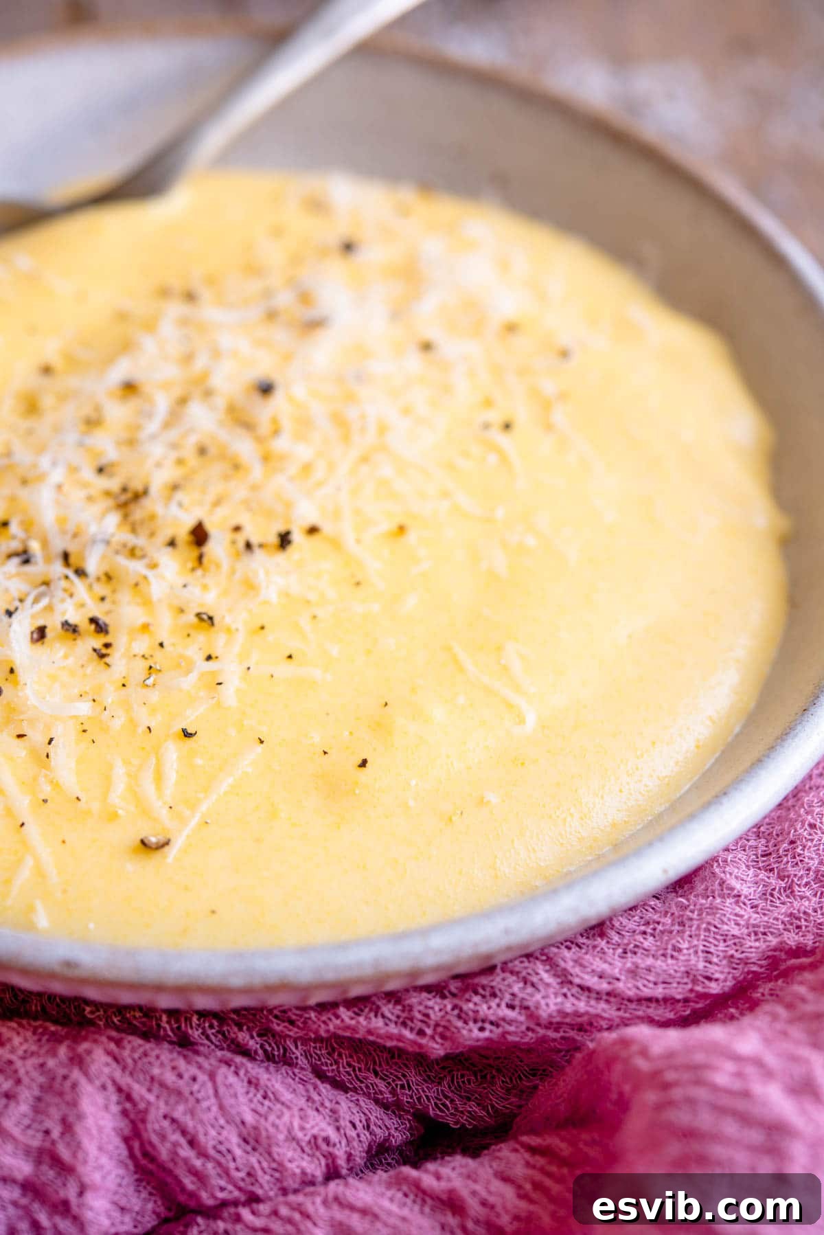 A side shot of creamy polenta in a bowl, showing its thick yet flowing texture