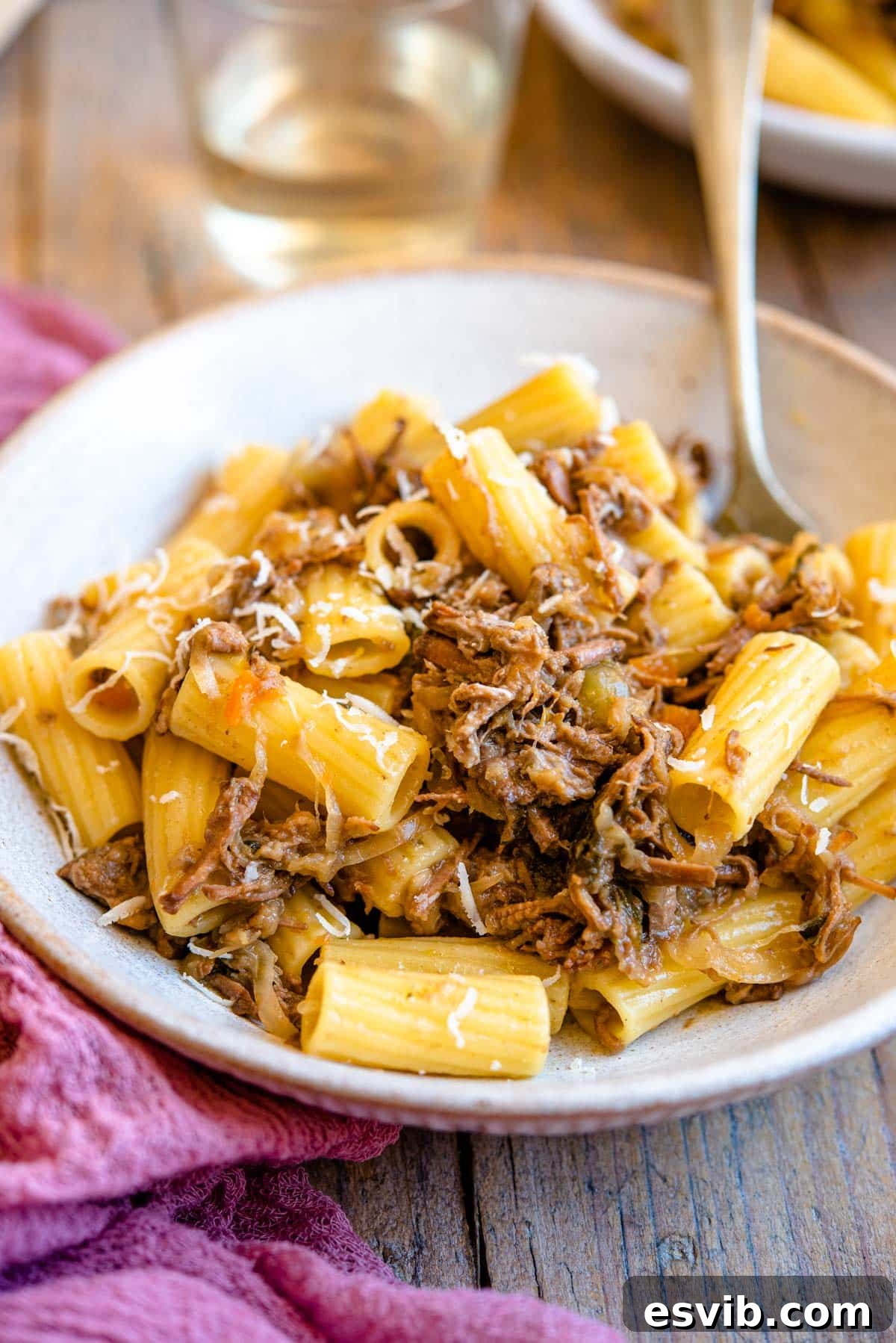 A side shot of a Neapolitan ragu tossed with rigatoni pasta in a rustic bowl