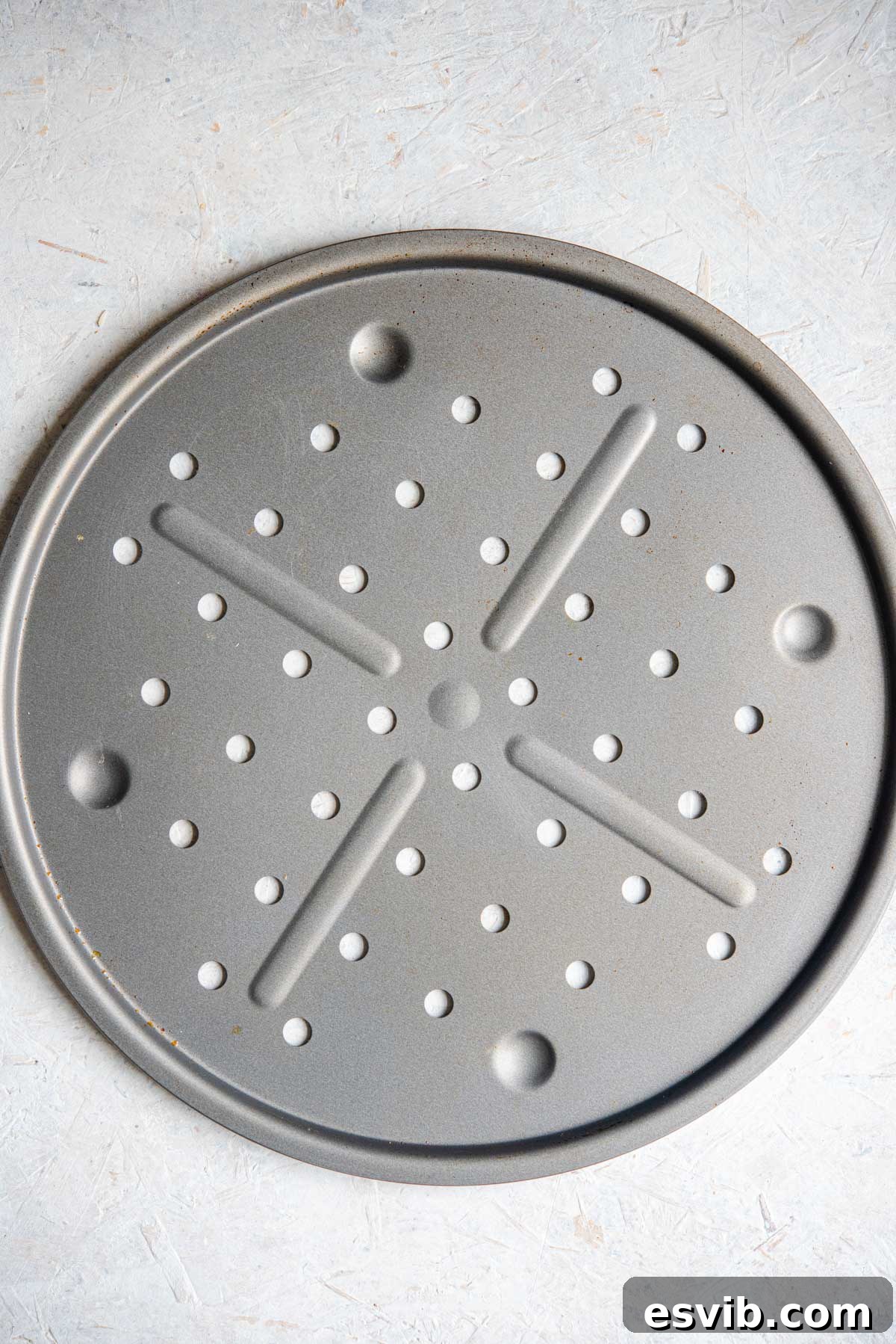 An overhead shot of a circular pizza tray with holes, showcasing its unique design.