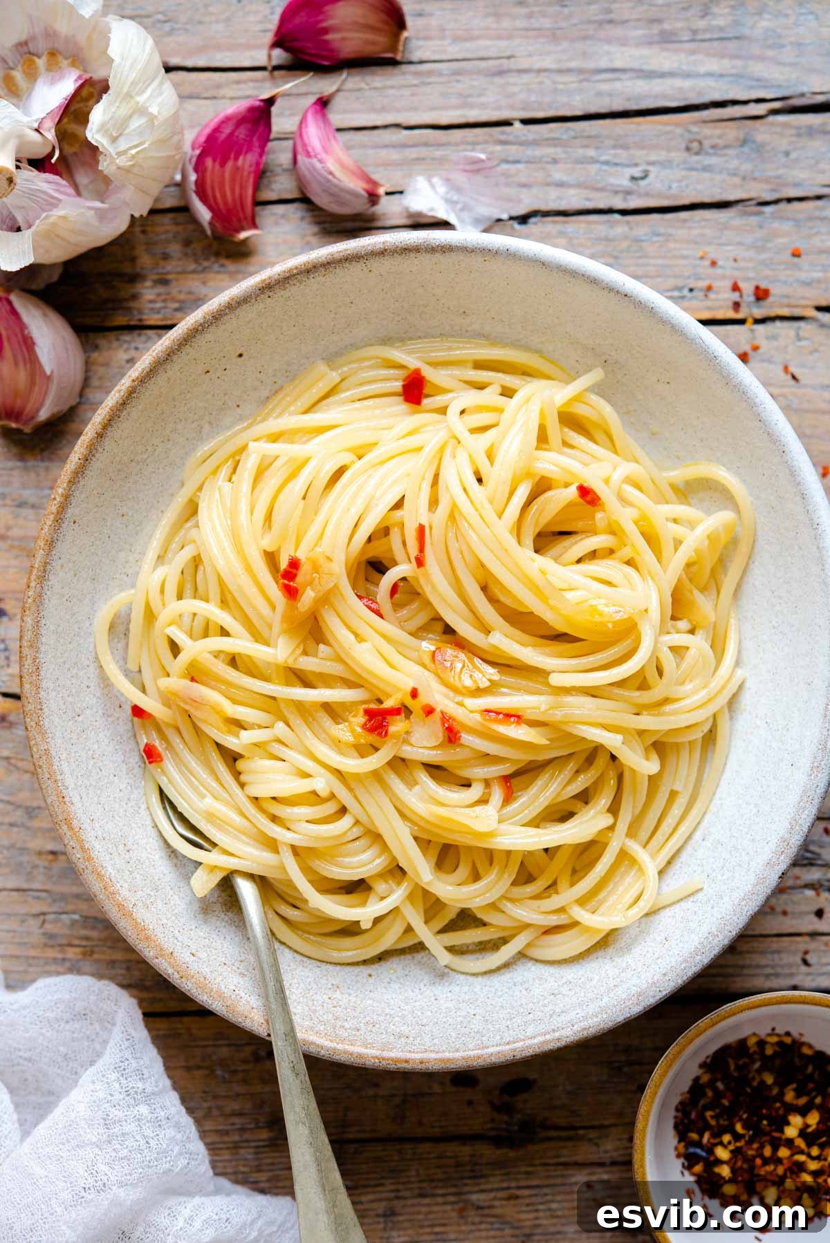 Spaghetti Aglio e Olio: Golden Garlic and Olive Oil Delight 2 Spaghetti Aglio e Olio in a rustic bowl sitting on a wooden surface, garnished with fresh parsley.
