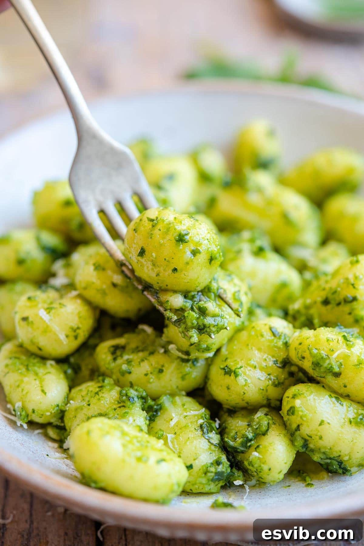 A close up of gnocchi and pesto sauce on a fork