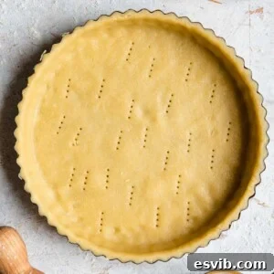 A square photo of raw sweet shortcrust pastry in a tart case, ready to be filled and baked.