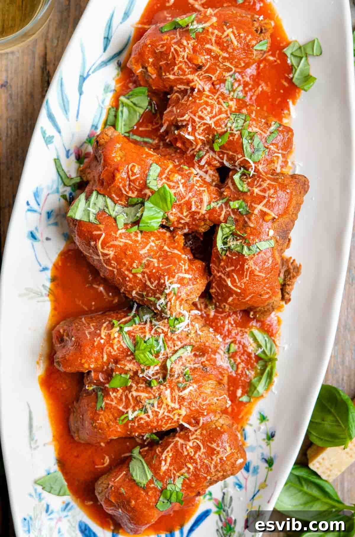 An overhead shot of braciole on a serving platter covered in tomato sauce
