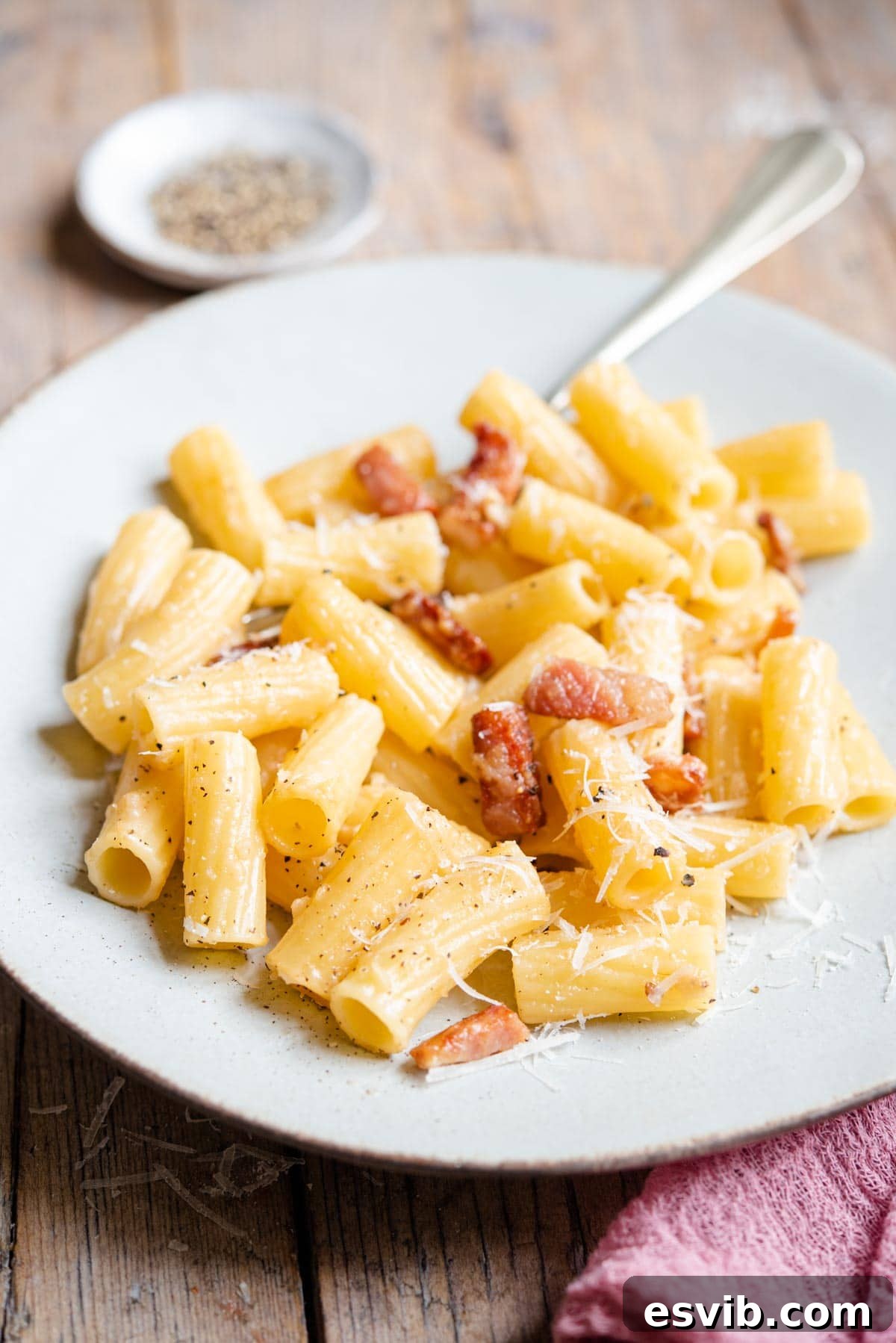 A beautiful side shot of a plate of Pasta alla Gricia, highlighting the texture of the pasta and the rich, creamy sauce.