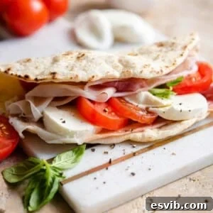 A close up of a piadina flatbread stuffed with tomatoes and mozzarella, ready to eat.
