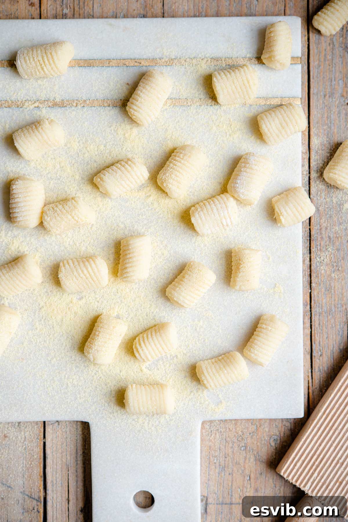A generous serving of perfectly cooked, homemade potato gnocchi waiting to be tossed in sauce, artfully arranged on a marble cutting board, ready for an authentic Italian meal.