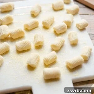 A side shot of potato gnocchi on a white marble cutting board