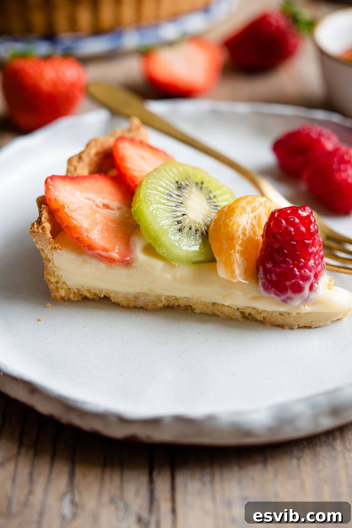 A perfectly sliced piece of Crostata di Frutta on a white plate, showcasing the flaky pastry, rich pastry cream, and vibrant fresh fruit topping.