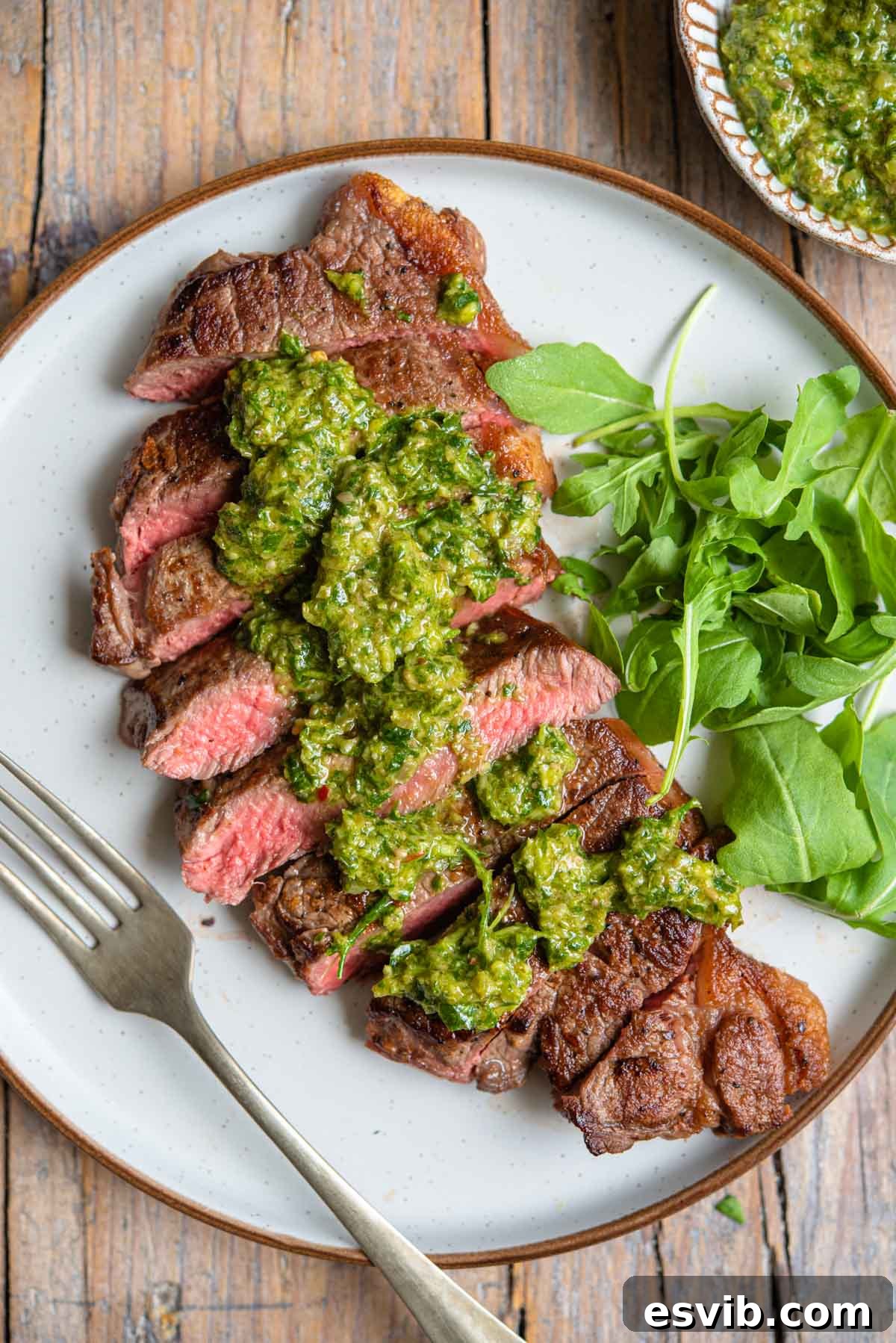Zesty Italian Green Sauce 2 Slices of juicy grilled steak adorned with a generous drizzle of homemade Italian Salsa Verde on a wooden board.