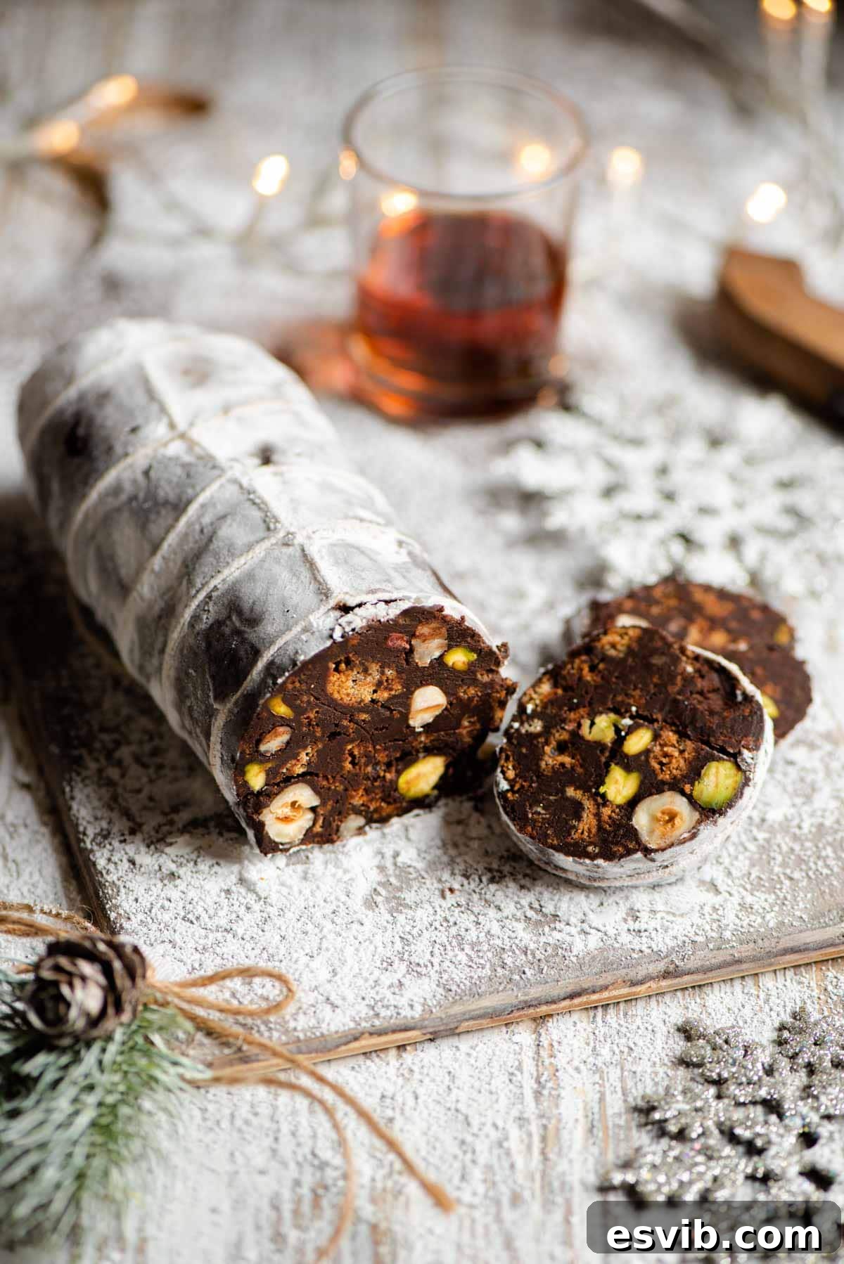 A chocolate salami on a wooden board with a few slices cut from it, showcasing its realistic appearance.