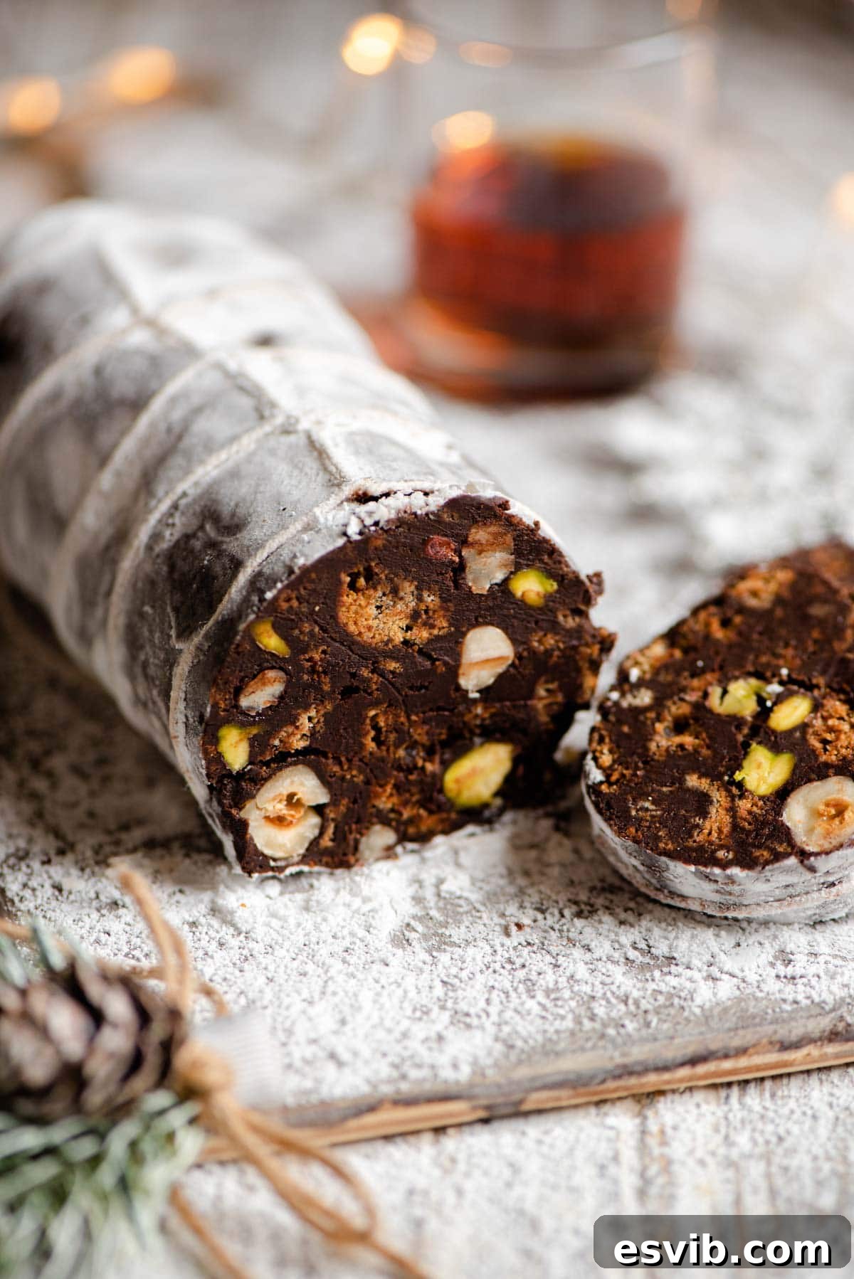 A close up of chocolate salami cut open showing the nuts and cookies inside, highlighting its tempting texture.