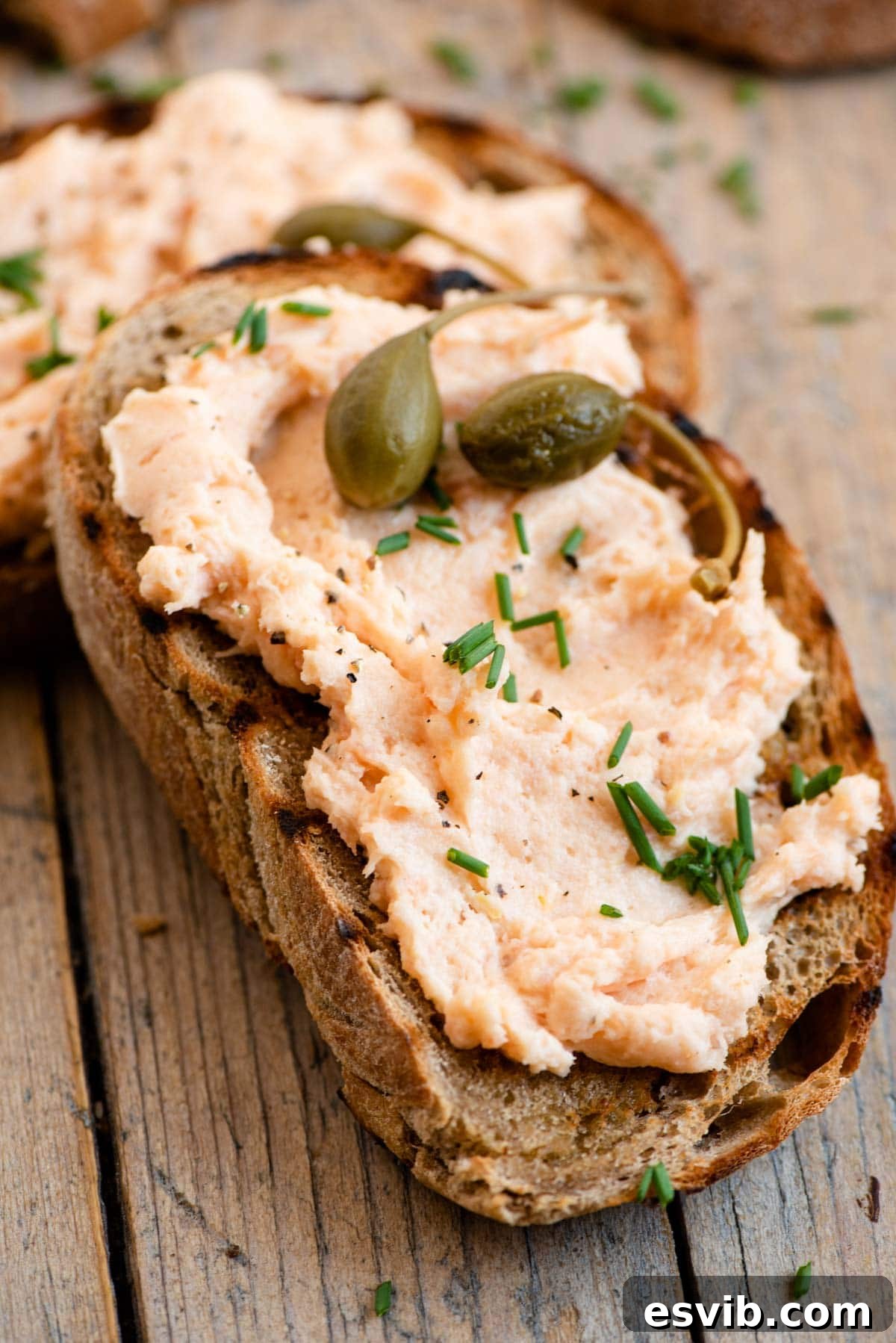 Smoked Salmon Crostini Bites 5 A tantalizing close-up shot of a single smoked salmon crostini, showcasing the creamy pate, fresh chives, and capers on perfectly toasted bread.