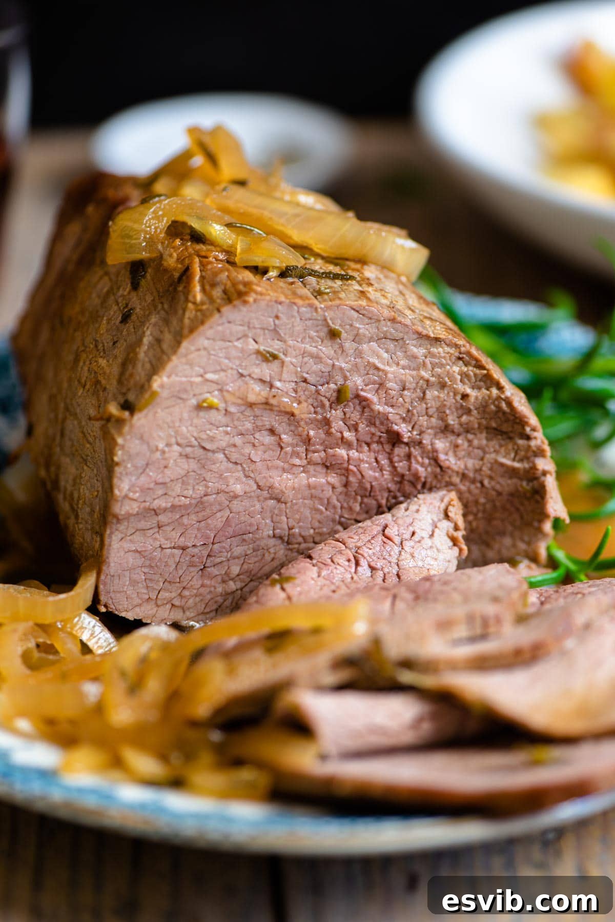 A close-up shot of perfectly cooked Italian roast beef slices generously topped with caramelized onions and a rich Marsala gravy, showcasing the juicy texture.