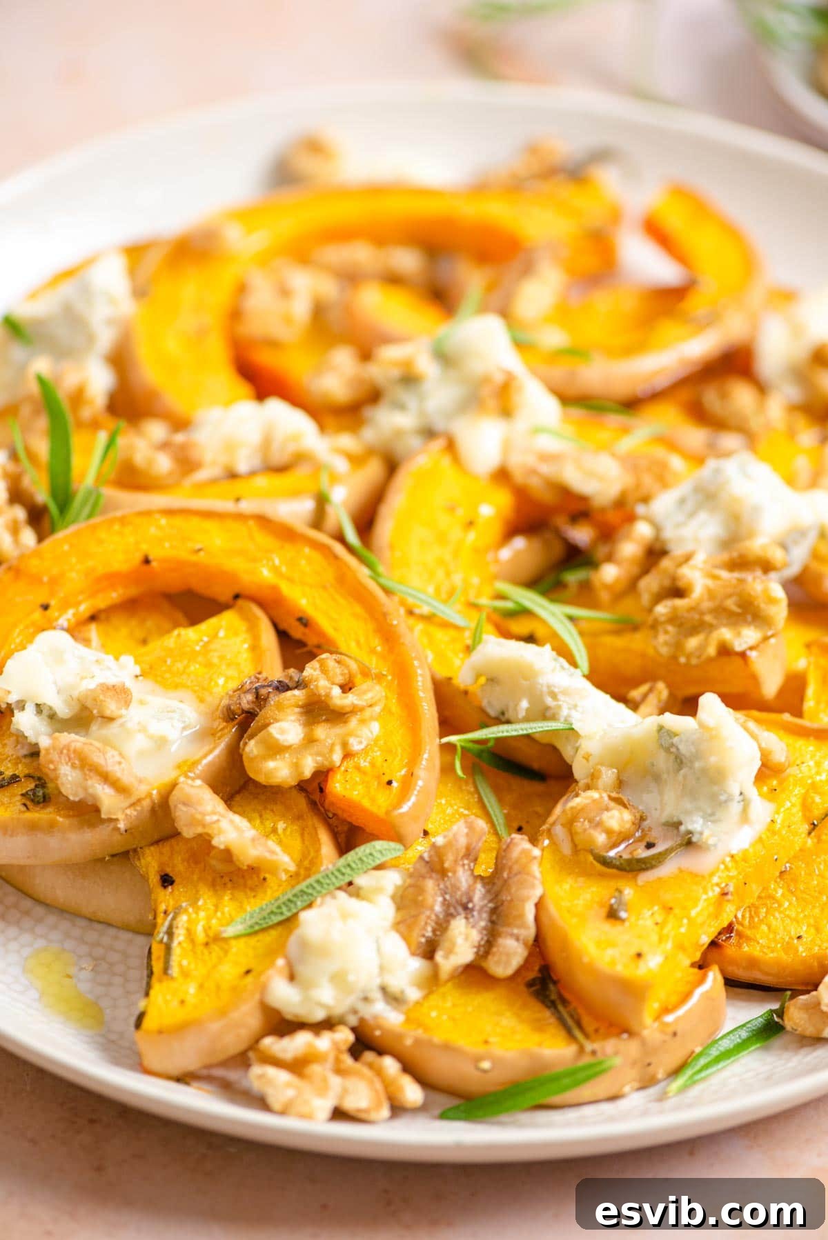 A close up of butternut squash on a serving plate with gorgonzola and walnuts