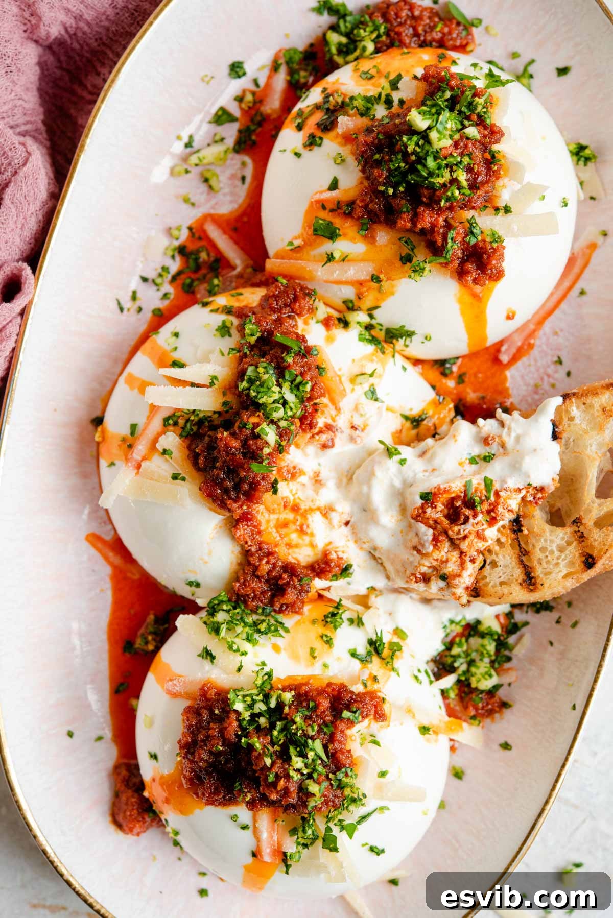 An overhead shot of burrata on a serving plate with 'Nduja and gremolata, ready to be served with ciabatta bread