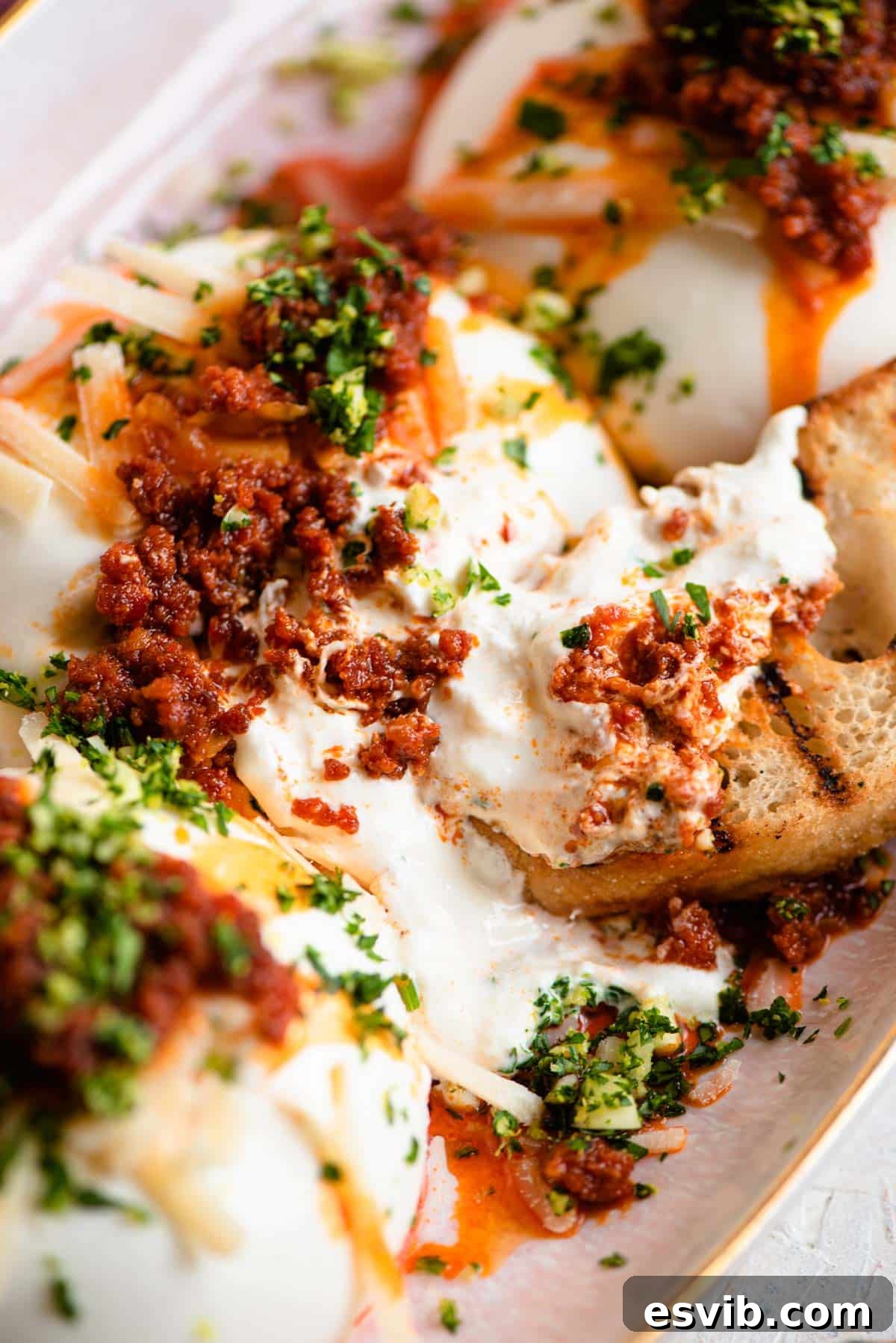 A close up of burrata cheese with crispy 'Nduja and fresh gremolata, served with char-grilled ciabatta bread
