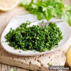 Gremolata on a small plate with wedges of lemon and parsley in the background