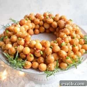 Struffoli honey balls in a ring shape on a cake stand covered in sprinkles