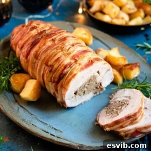 A close up of a stuffed turkey breast on a platter with roast potatoes