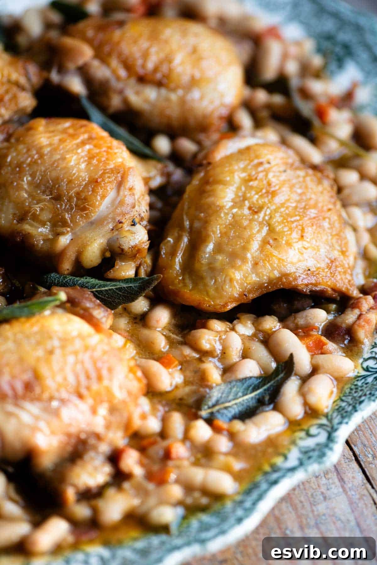 Rustic Chicken and Bean Braise with Sage and Pancetta 6 A close up of braised chicken on a serving plate with beans and sage.