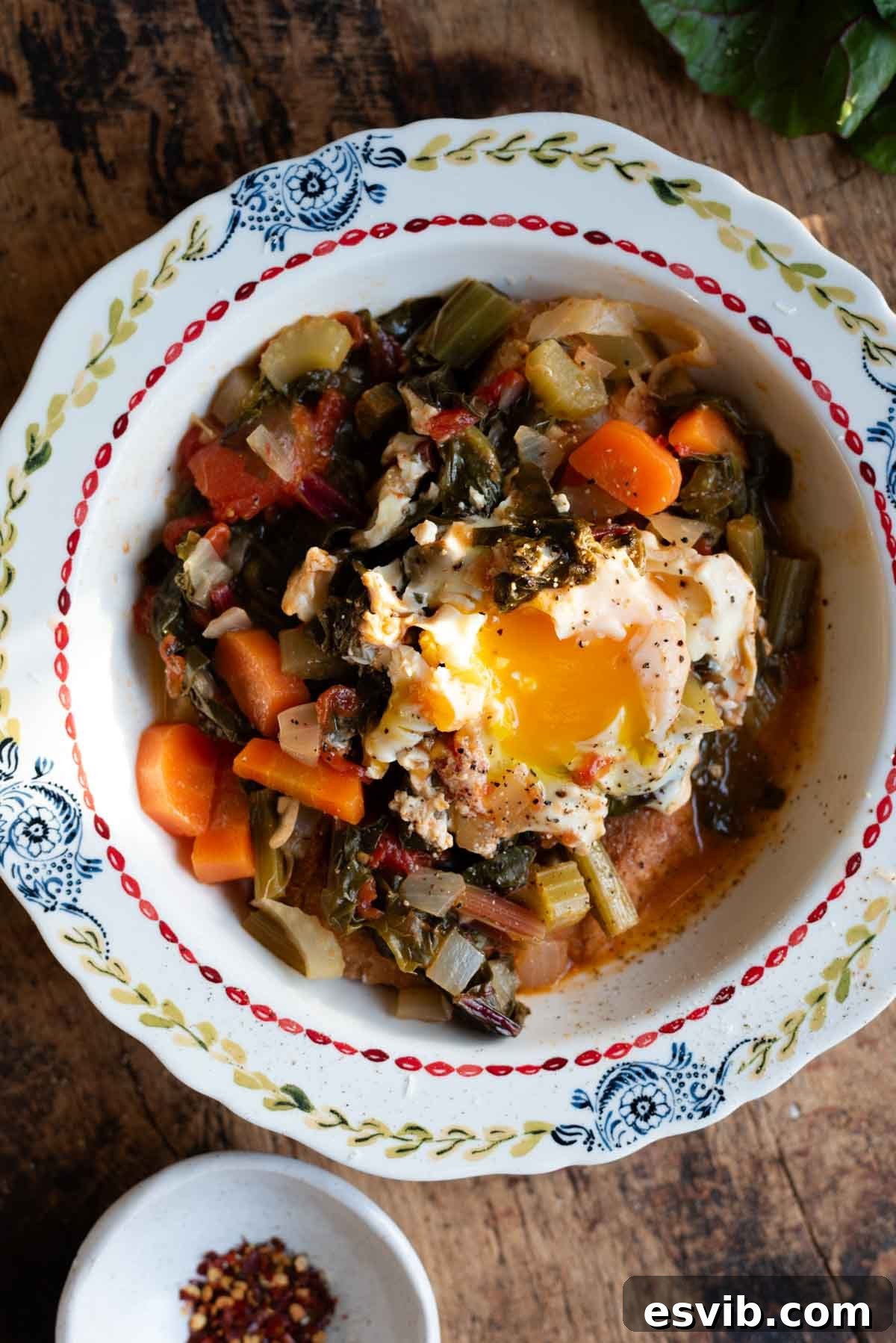 A beautiful vintage-style bowl filled with traditional Tuscan Acquacotta soup, garnished with fresh herbs and a perfectly poached egg on top, resting on a rustic table.