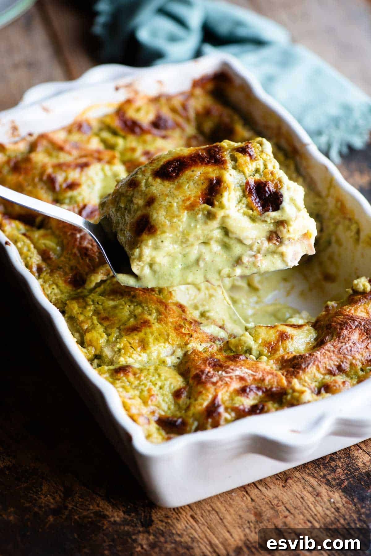 A spatula picking a slice of pistachio lasagna from a baking dish.
