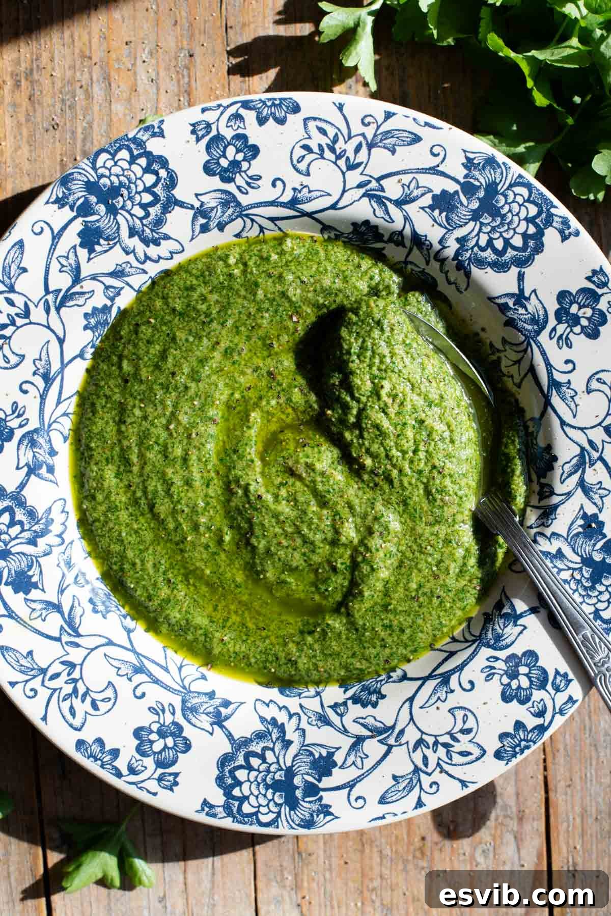 An inviting overhead shot of Tuscan salsa verde presented in a charming blue and white bowl, placed on a wooden surface, ready to be enjoyed.