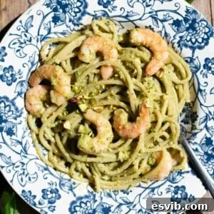 Emerald Coast Pistachio Shrimp Pasta 5 A close-up photograph of Sicilian pistachio spaghetti with plump shrimp on a blue floral plate, ready to eat.