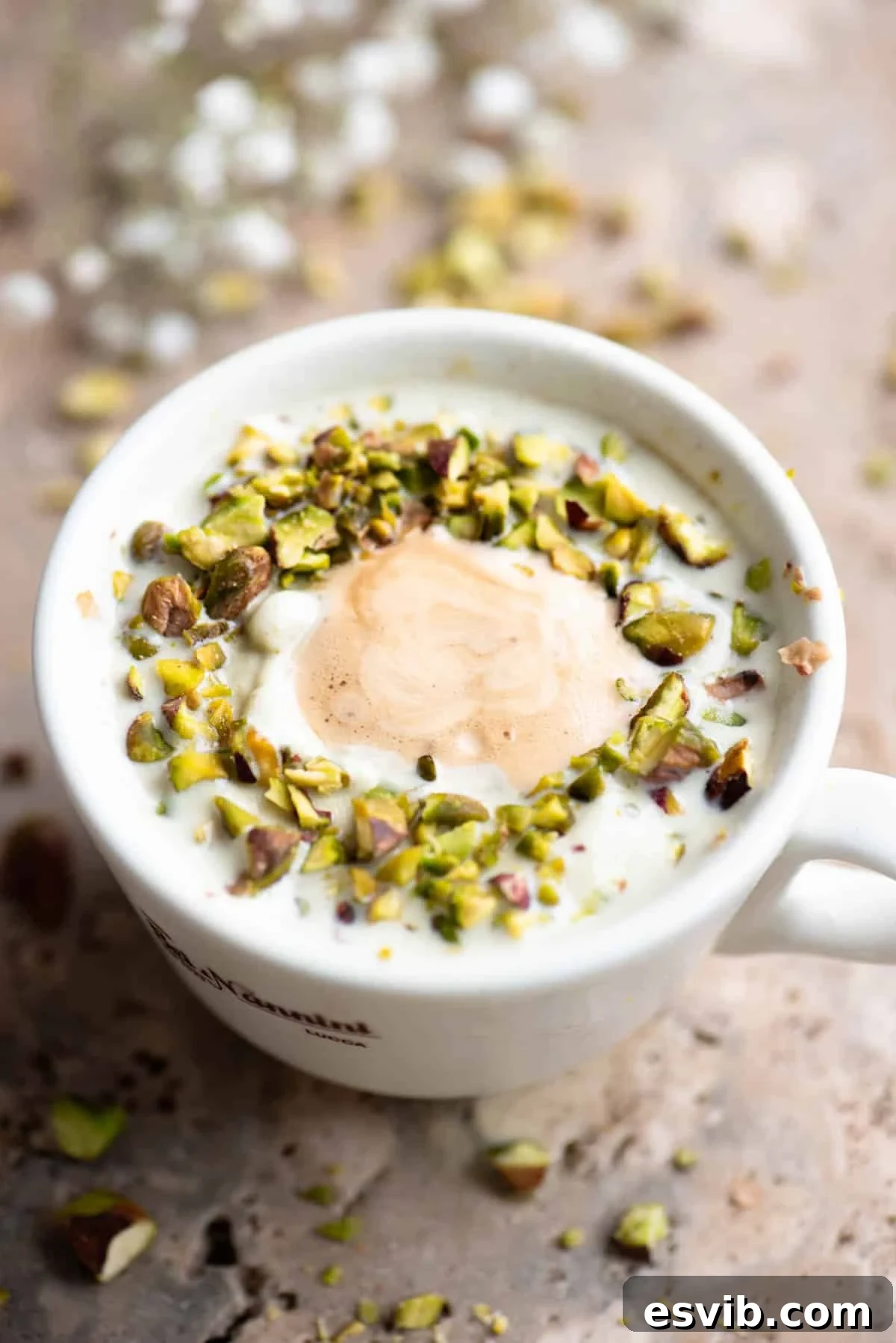 A pistachio affogato topped with chopped pistachios on a travertine surface.