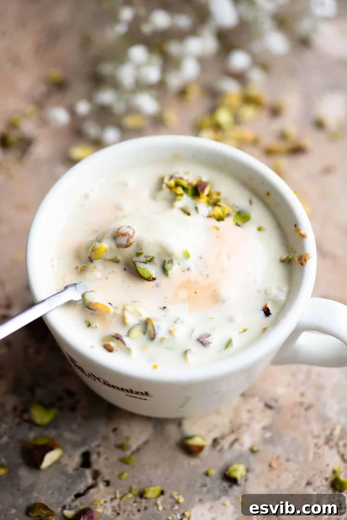 A pistachio affogato mixed in a mug with a spoon inside.