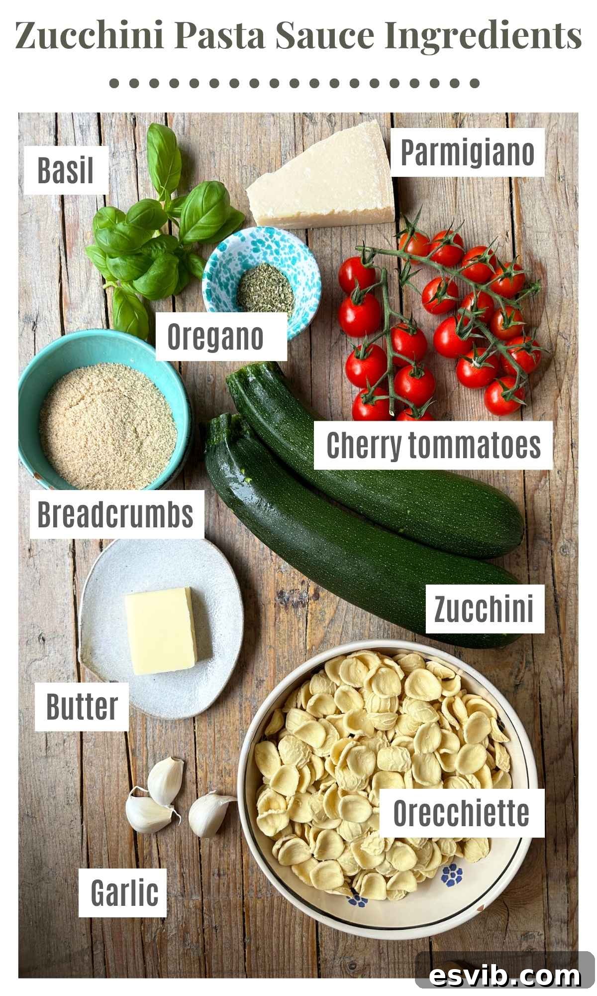 An overhead shot of the ingredients needed to make a zucchini butter pasta. Basil, parmigiano, cherry tomatoes, breadcrumbs, zucchini, orecchiette, garlic, butter and oregano.