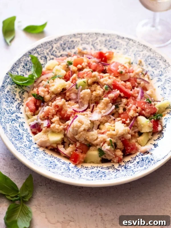 Authentic Tuscan Panzanella Salad in a blue patterned bowl with basil around.