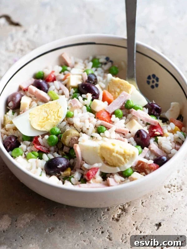 A traditional Italian rice salad in a bowl sitting on a rustic stone work top.