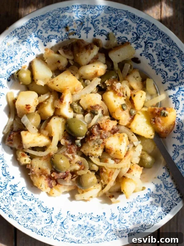 Sicilian potatoes in a blue bowl with olives and capers.