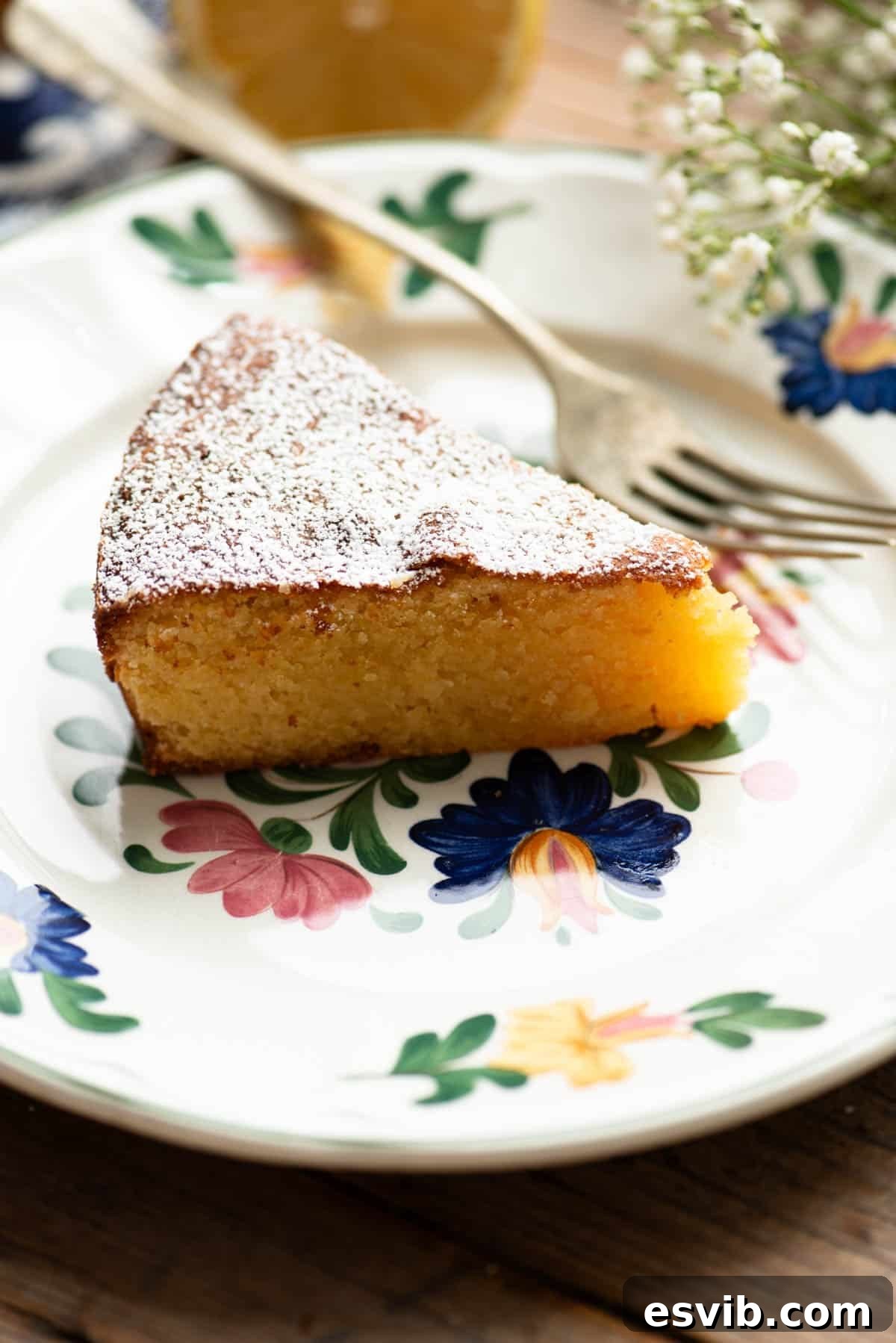 A close up of a slice of white chocolate caprese cake on an Italian floral plate.