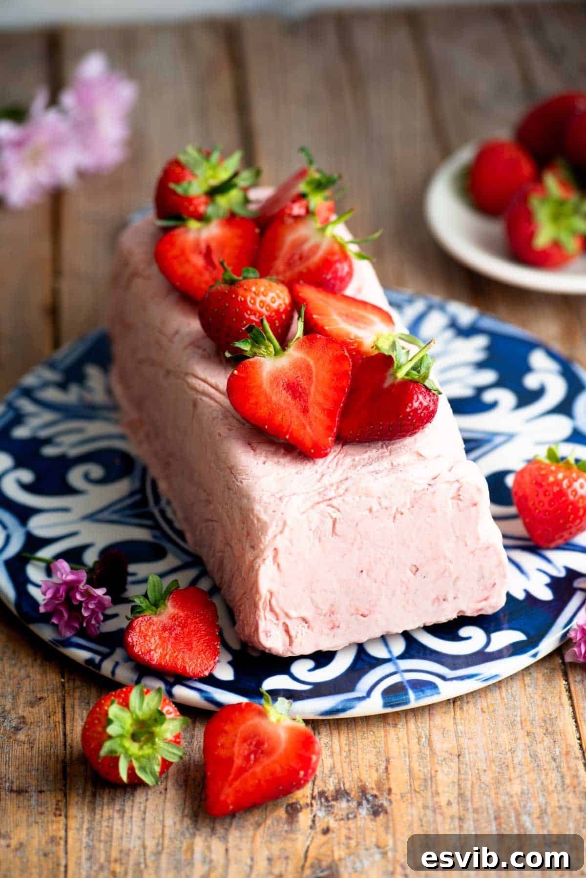 Strawberry semifreddo on a blue and white ceramic serving board topped with cut strawberries.