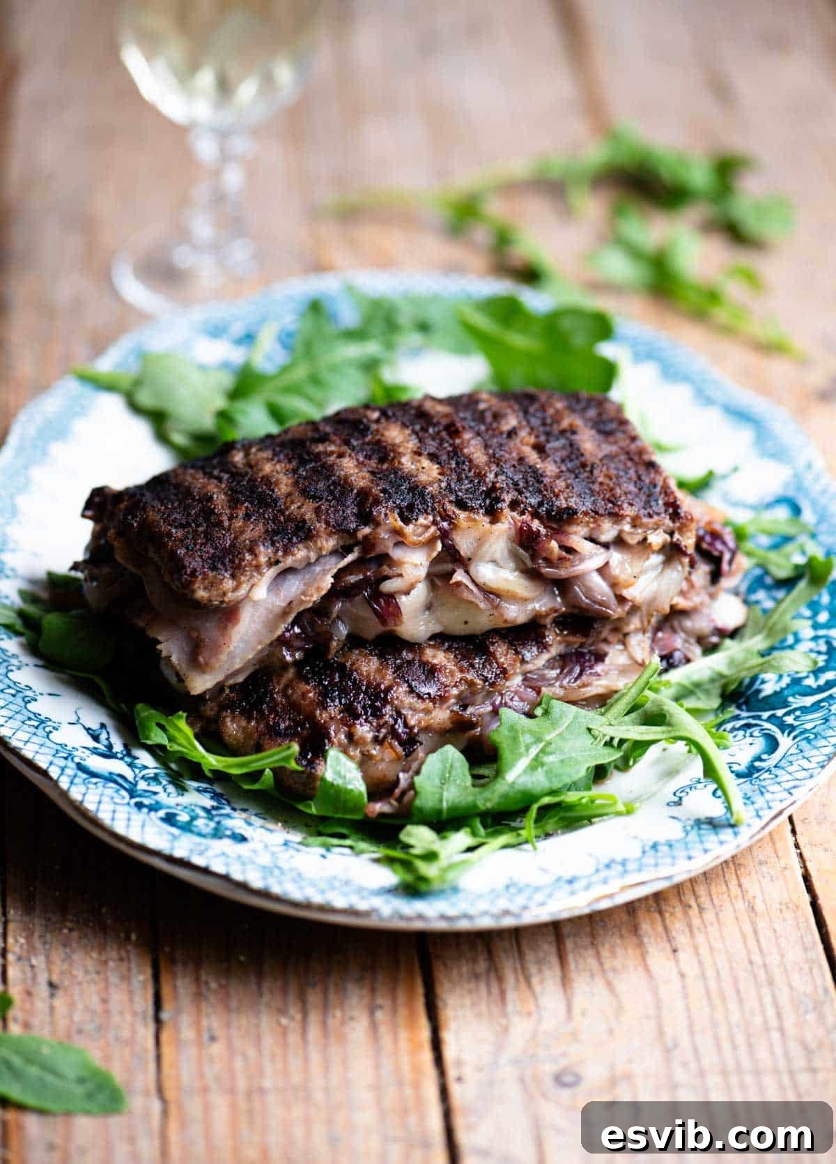 Two slices of stuffed beef stuffed with cheese, radicchio and porchetta on top of each other on a blue plate garnished with arugula.