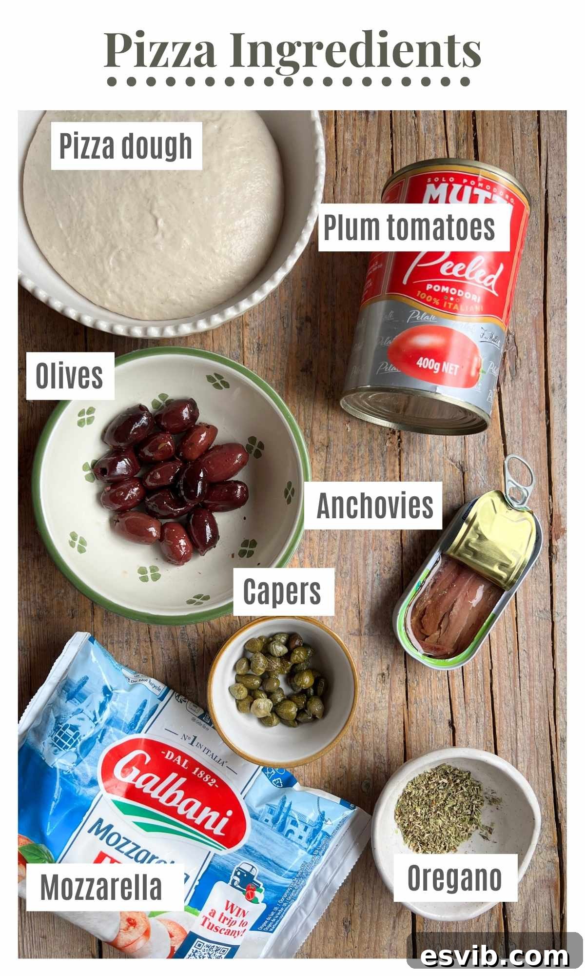 An overhead shot of pizza ingredients on a rustic wooden surface. The text labels read; pizza dough, plum tomatoes, olives, capers, anchovies, mozzarella and oregano.